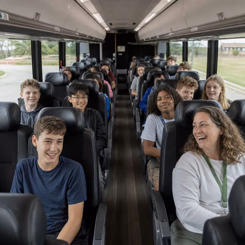 Group boarding a white charter bus for School Transportation transportation in New Orleans